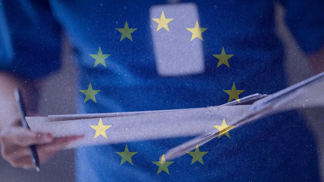 Cilvēks pārskata dokumentus ar pildspalvu rokās, fonā Eiropas Savienības karogs.